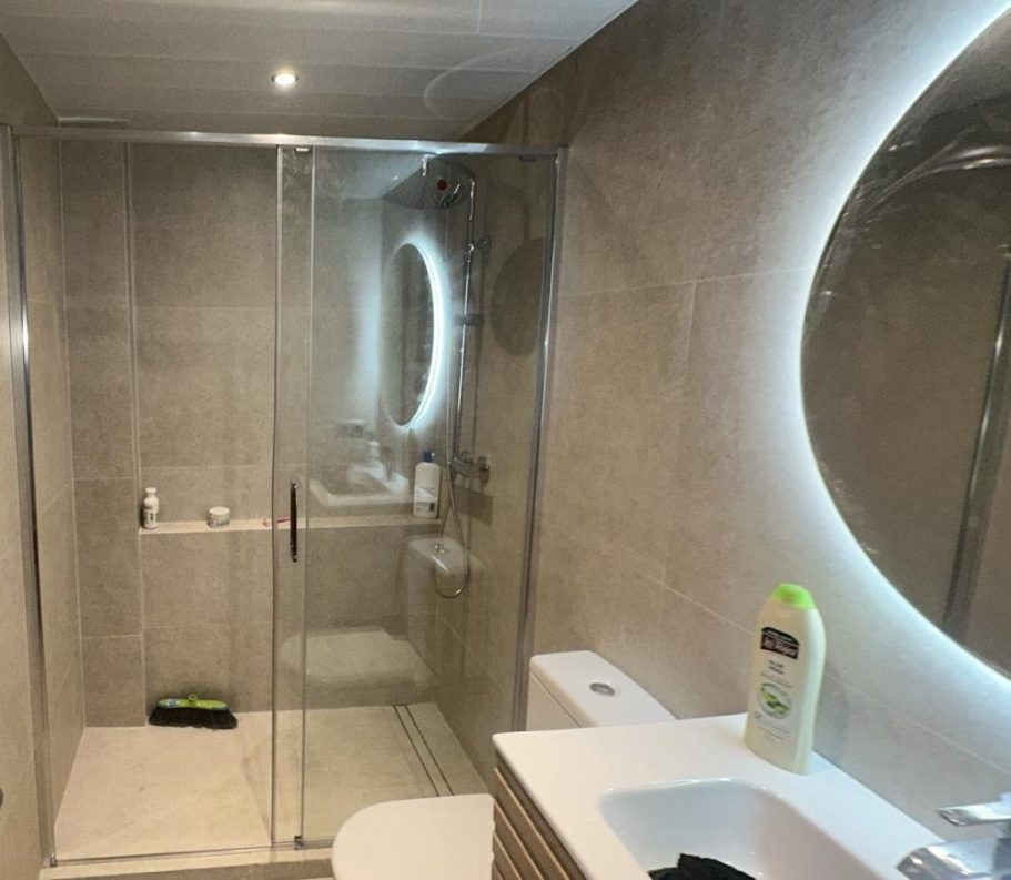 Reforma de baño moderno con plato de ducha y mampara en Barcelona
